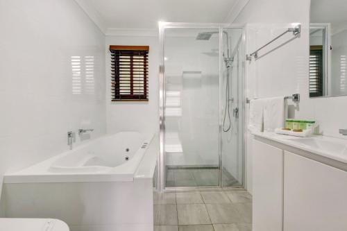 a white bathroom with a tub and a shower at Kiama Harbour Cabins in Kiama