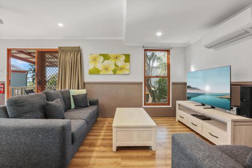 a living room with a couch and a tv at Kiama Harbour Cabins in Kiama