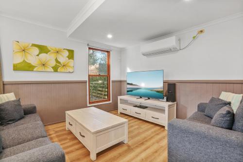 a living room with two couches and a tv at Kiama Harbour Cabins in Kiama