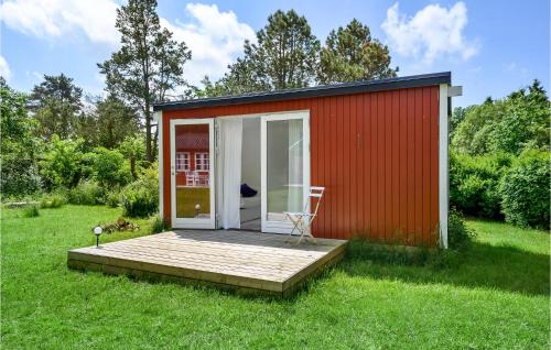 a red shed with a deck in the grass at Gorgeous Home In Eskebjerg With Wifi in Eskebjerg