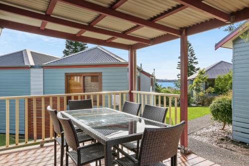 a patio with a table and chairs on a deck at Kiama Harbour Cabins in Kiama
