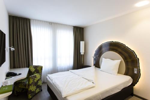 a hotel room with a bed and a chair at Taome Feng Shui Stadthotel Breisgau in Emmendingen