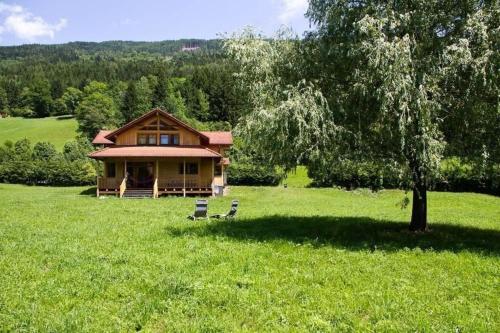 a house in the middle of a field with a tree at Komfortables Vollholzhaus in Fischertratten in Hilpersdorferau