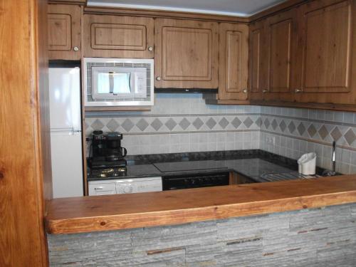 a kitchen with wooden cabinets and a white refrigerator at Casa La Bordeta Remondillo in San Juan de Plan