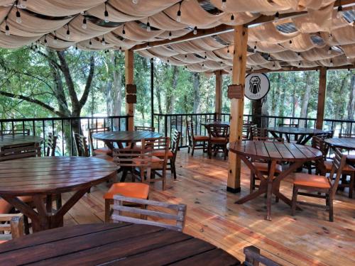 un ristorante con tavoli e sedie in legno su una terrazza di ASGARD RESORT GUATEMALA a Santiago Sacatepéquez