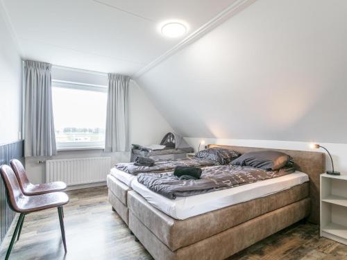 a bedroom with a large bed and a chair at Bij de Buren in Oploo