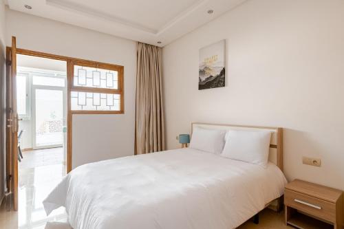 a bedroom with a white bed and a window at New Luxurious apartment Agdal Rabat center in Rabat