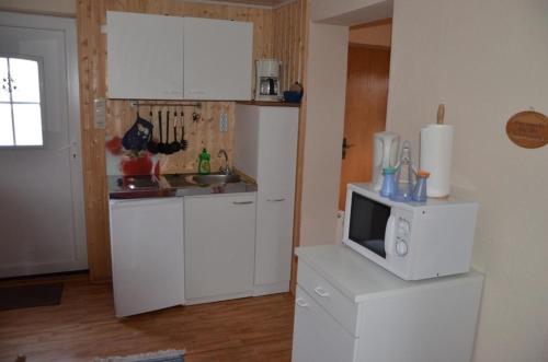 a kitchen with white cabinets and a microwave at Ferienwohnung Krummhörn Upleward in Krummhörn