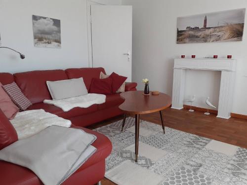 a living room with a red couch and a table at Ferienwohnung in Stoltebüll mit Kleiner Terrasse in Stoltebüll