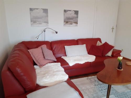 a red couch with pillows in a living room at Ferienwohnung in Stoltebüll mit Kleiner Terrasse in Stoltebüll