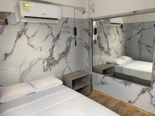 a small room with two beds and a mirror at Hotel Rancho Grande in Barranquilla