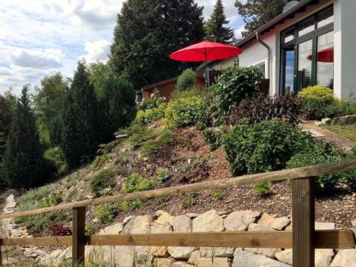 a house with a red umbrella on top of a hill at Modern ausgestattetes Ferienhaus mit möblierter Südhang-Terrasse im Altenautal in Husen