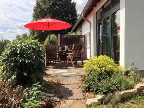 a patio with a table and chairs with a red umbrella at Modern ausgestattetes Ferienhaus mit möblierter Südhang-Terrasse im Altenautal in Husen