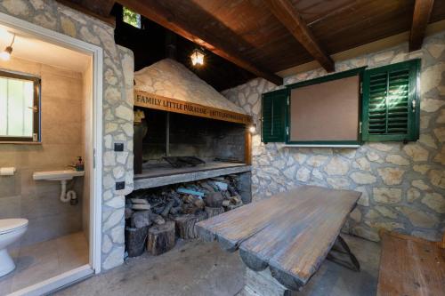 a stone kitchen with a wooden table and a fireplace at Family Little Paradise in Ružić