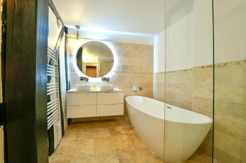 a bathroom with a tub and two sinks and a mirror at La Dame Blanche - Appartement hypercentre historique - Parking privé in Bourges