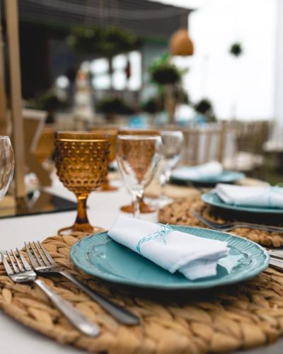 a table with a blue plate and forks and glasses at Hotel Trocadero in Concón