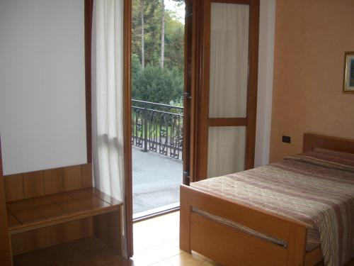 1 dormitorio con puerta que da a un balcón en Albergo Il Castellino en Boario Terme