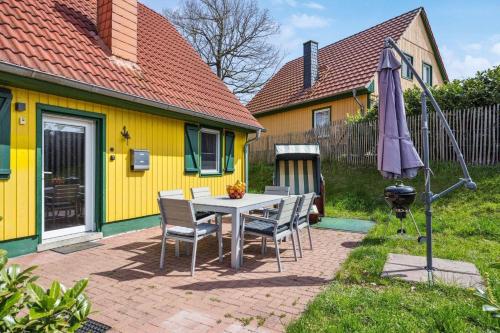 a yellow house with a table and chairs and an umbrella at Komplett umzäuntes Ferienhaus Plauer See mit Hund in Zislow