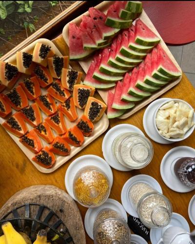 a table with a tray of fruit and other foods at Pousada Aracê in Pedra Azul