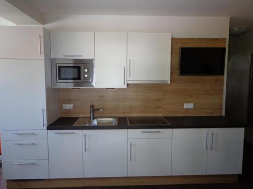 a kitchen with white cabinets and a sink and a microwave at Ladis Living in Ladis