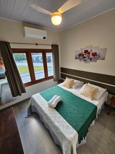 a bedroom with a large bed with a green blanket at Pousada Aracê in Pedra Azul