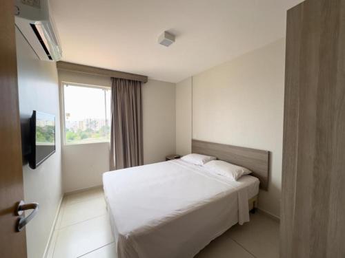 Un dormitorio con una cama blanca y una ventana. en ATRIUM THERMAS Residence Service, en Caldas Novas