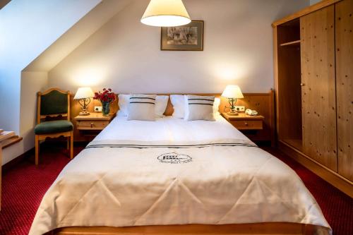 a bedroom with a large bed with two tables and a chair at Hotel Pod Ciżemką in Sandomierz