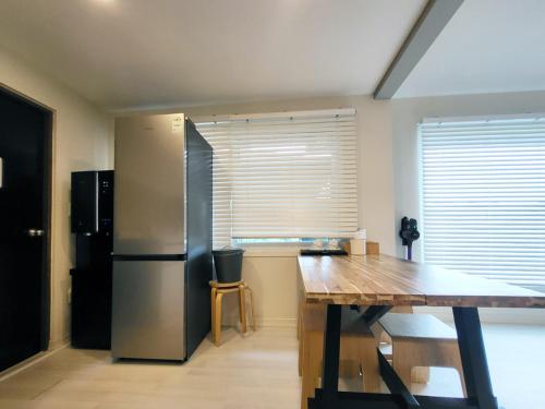 a kitchen with a stainless steel refrigerator and a wooden table at Penatess Pool Villa in Chungju
