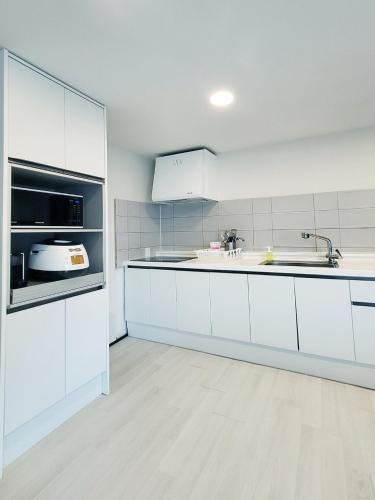 a kitchen with white cabinets and a sink at Penatess Pool Villa in Chungju