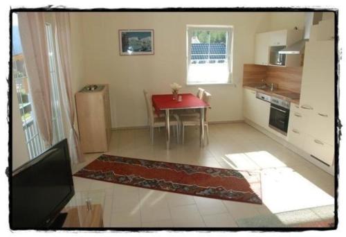 a small kitchen with a red table and a red rug at Ferienwohnung Kammblick in Bad Mitterndorf in Bad Mitterndorf