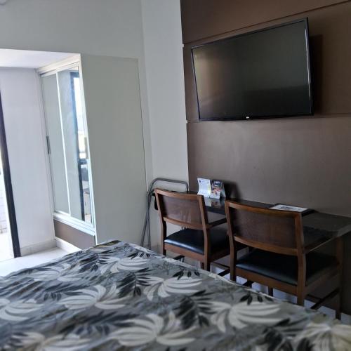 a hotel room with a bed and two chairs and a flat screen tv at hotel tambau flat particular 605 in João Pessoa