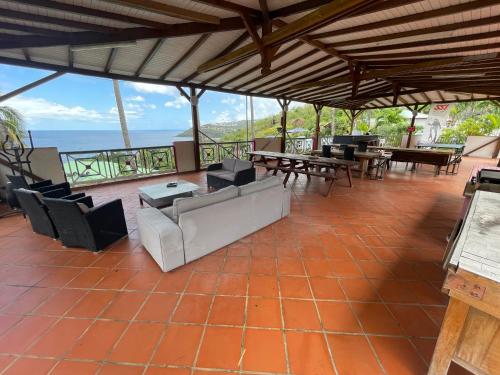 a large patio with tables and chairs and the ocean at Le Nid Tropical in Bouillante