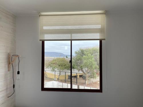 a window in a white room with a window shade at Hostal CKAIR in Bahia Inglesa