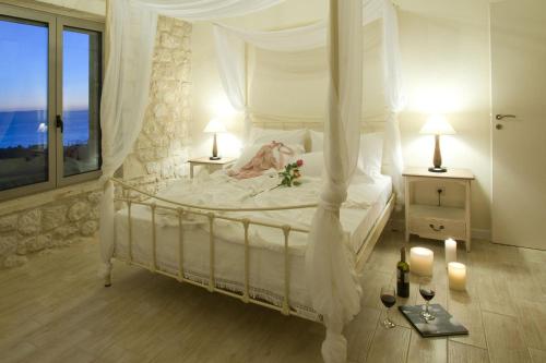 a bedroom with a white canopy bed with a window at Poliana Estate Villas in Riglia