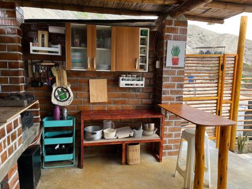 a kitchen with a brick wall and a table at Cabaña de Campo Huaral, hermosas vistas Piscina in Huaral