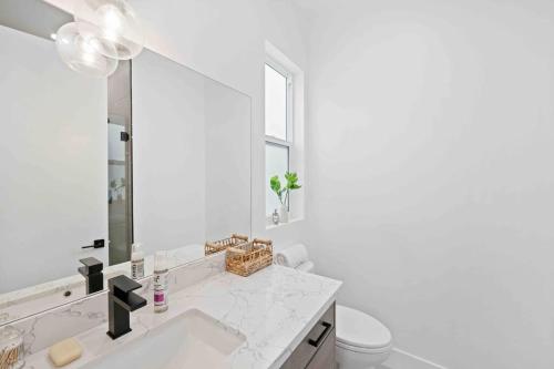 Un baño blanco con lavabo y espejo. en Prime Location 3BD 3BA Luxury Living in LA, en Los Ángeles