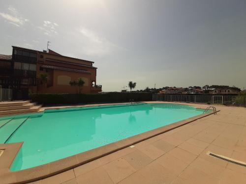 une grande piscine bleue devant un immeuble dans l'établissement Studio cabine avec piscine et tennis, Capbreton - FR-1-239-809, à Capbreton