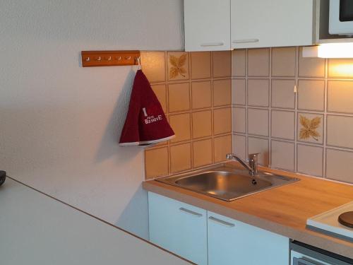 - une cuisine avec un évier et un sac rouge sur le mur dans l'établissement Studio cabine avec piscine et tennis, Capbreton - FR-1-239-809, à Capbreton