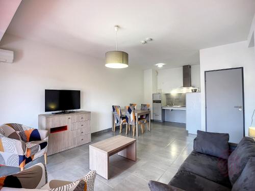 un salon avec un canapé, une télévision et une table dans l'établissement Appartement F2 PMR, climatisé, avec terrasse et parking privé, au cœur de Lamalou-les-Bains - FR-1-451-194, à Lamalou-les-Bains