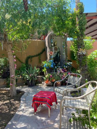 a garden with two chairs and a table and flowers at Casa La Castañeda in Loreto