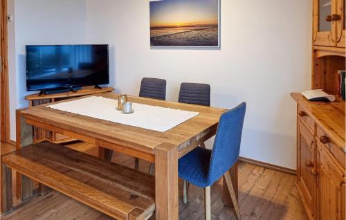 a dining room table with blue chairs and a television at Awesome Home In Friedrichskoog-Spitze in Friedrichskoog-Spitz