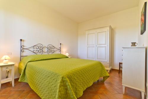 sypialnia z łóżkiem z zieloną narzutą w obiekcie La Fattoria di Tirrenia w mieście Tirrenia