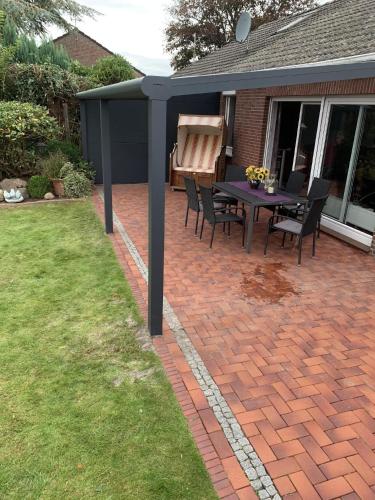 a patio with a table and chairs on a brick yard at Ferienhaus in Hage mit Garten, Terrasse und Grill in Hage