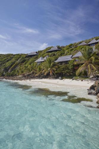 a beach with a group of houses and the ocean at Mandarin Oriental, Canouan in Canouan