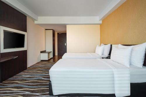 a hotel room with two beds and a flat screen tv at Swiss-Belhotel Makassar in Makassar