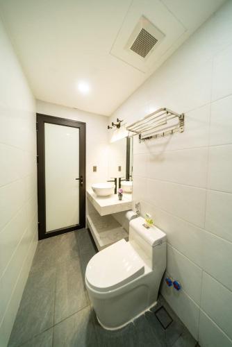 a white bathroom with a toilet and a sink at 2CE APARTMENT & HOTEL in Hai Phong