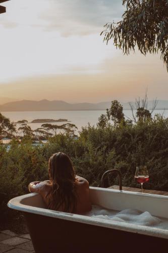 a woman sitting in a bath tub with a glass of wine at The Sandy Sister in Dodges Ferry