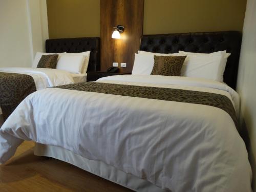 two beds in a hotel room with white sheets at Siena Hotel in Cuenca