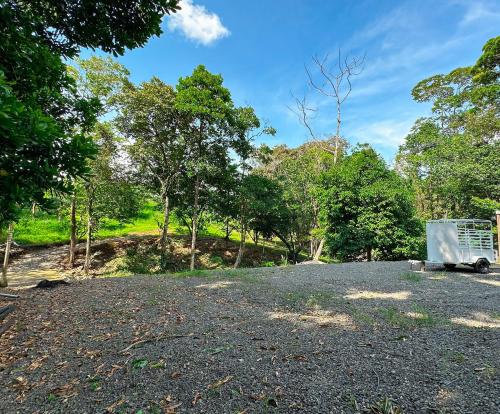 a gravel parking lot with a trailer in a forest at Cabañas Vistas de Altura por Hermanos Solano in San Francisco