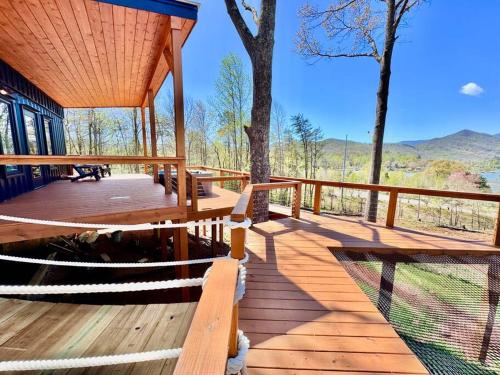 una terraza de madera con mesa y bancos. en Hiawassee Glamping Container Treehouse, en Hiawassee